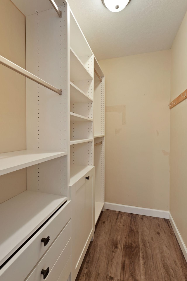 walk in closet with dark hardwood / wood-style flooring