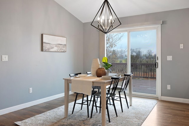 dining room featuring hardwood / wood-style floors, lofted ceiling, and an inviting chandelier