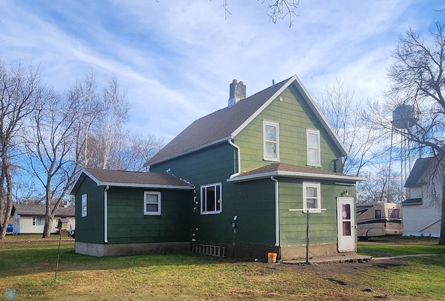 rear view of property featuring a lawn and a chimney