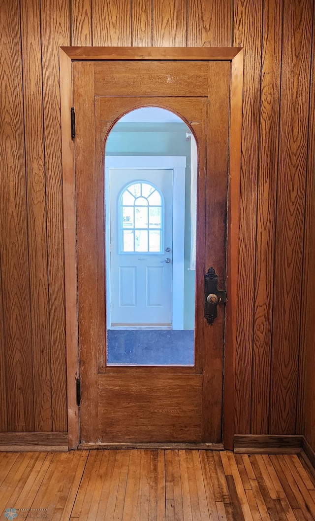 details with arched walkways, wooden walls, and wood finished floors