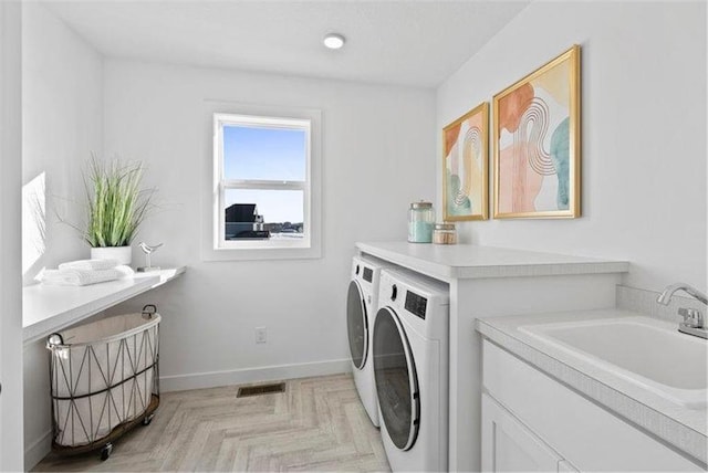 clothes washing area featuring sink, light parquet floors, and washing machine and clothes dryer