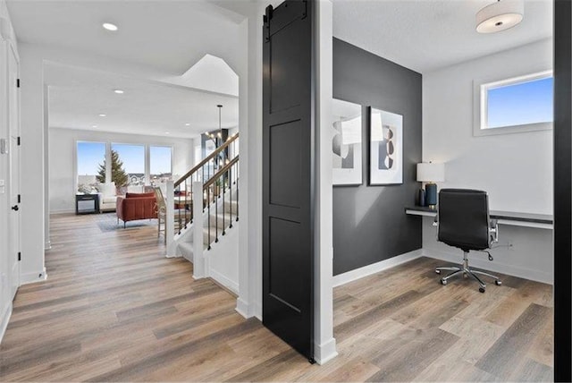 home office featuring a barn door, hardwood / wood-style flooring, and built in desk