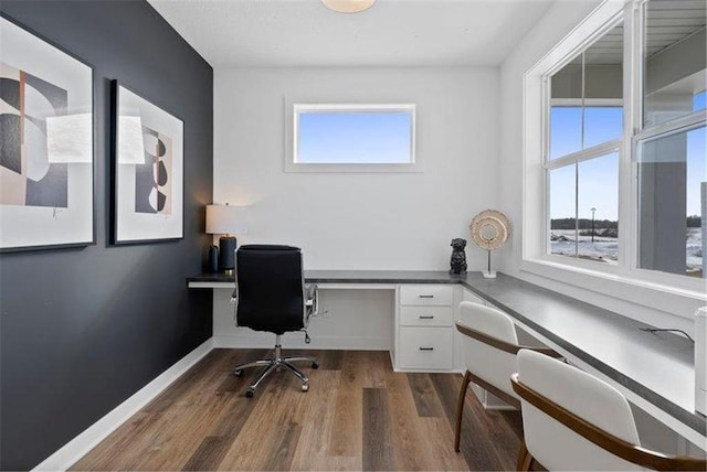 office with built in desk and dark hardwood / wood-style floors