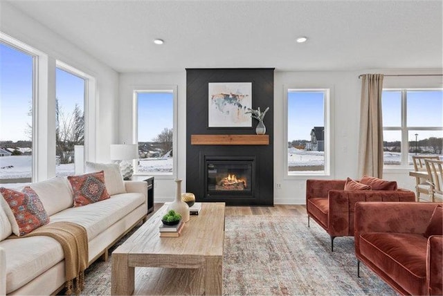 living room featuring light hardwood / wood-style flooring, a wealth of natural light, a textured ceiling, and a fireplace