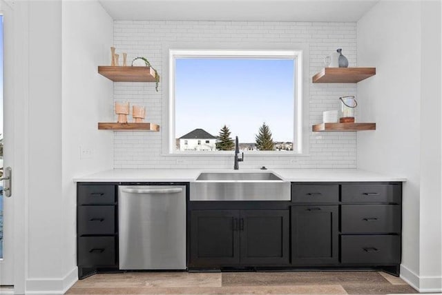 kitchen featuring dishwasher, decorative backsplash, sink, and light hardwood / wood-style flooring