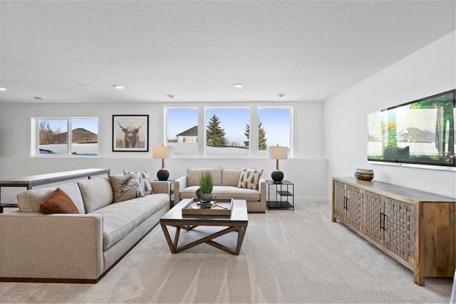 living room with a wealth of natural light, a textured ceiling, and light colored carpet