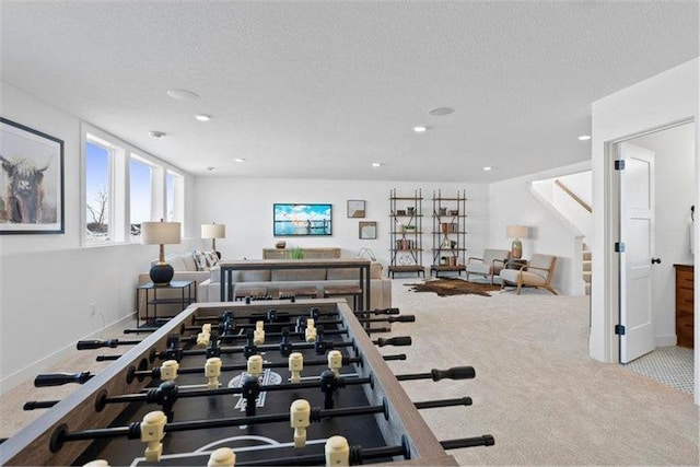 recreation room with a textured ceiling and light colored carpet