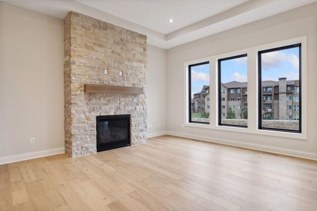 unfurnished living room with light hardwood / wood-style floors and a stone fireplace