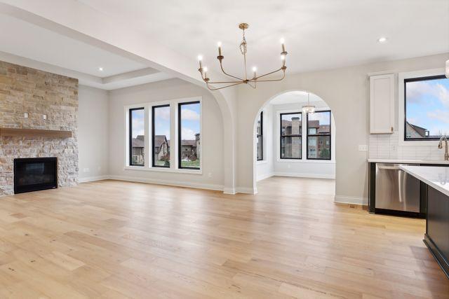 unfurnished living room with a fireplace, light wood-type flooring, and a chandelier