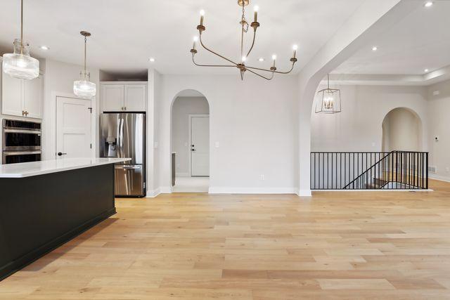 kitchen with pendant lighting, white cabinets, light hardwood / wood-style floors, and appliances with stainless steel finishes