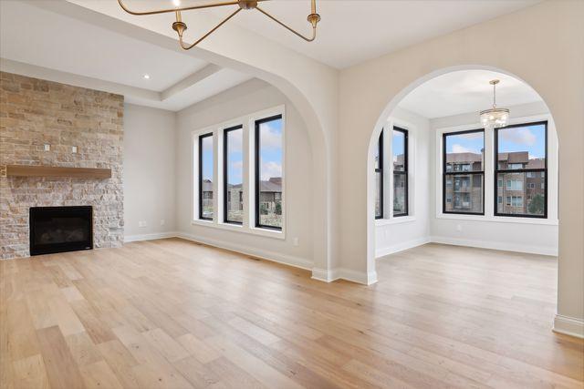 unfurnished living room with a stone fireplace, plenty of natural light, and light hardwood / wood-style flooring