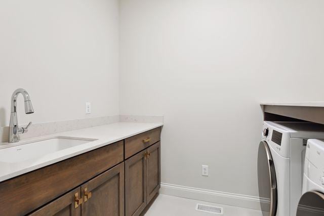 clothes washing area with washer and clothes dryer, light tile patterned floors, cabinets, and sink