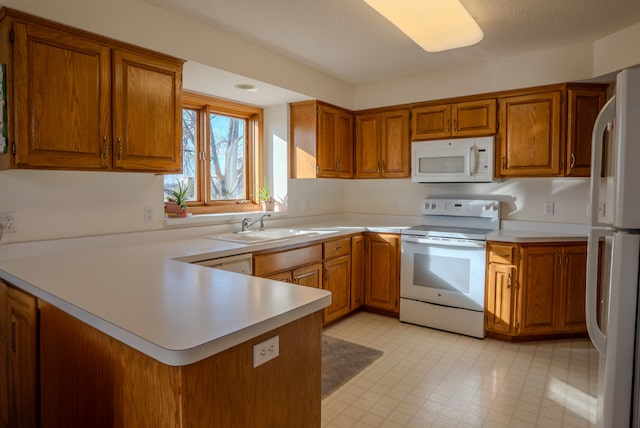 kitchen featuring kitchen peninsula, white appliances, and sink