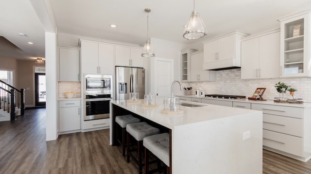 kitchen featuring white cabinetry, sink, stainless steel appliances, an island with sink, and decorative backsplash