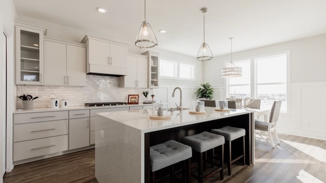 kitchen featuring sink, gas stovetop, white cabinetry, and an island with sink