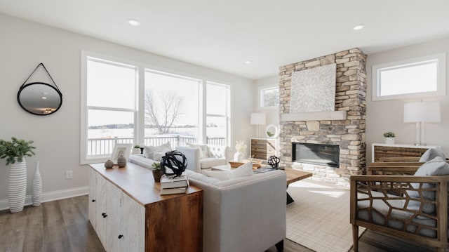 living room with a stone fireplace and dark wood-type flooring