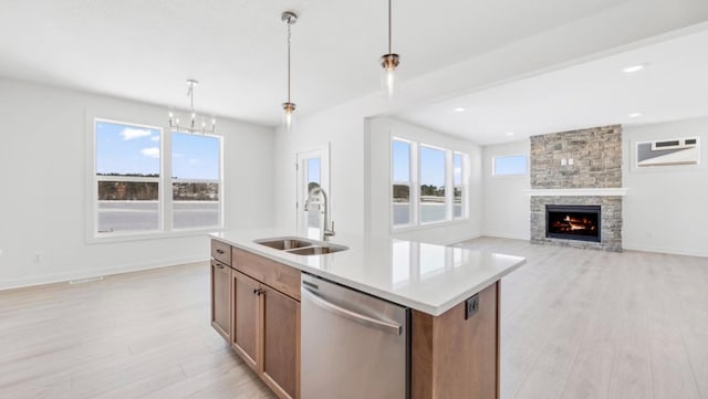 kitchen featuring open floor plan, light countertops, stainless steel dishwasher, pendant lighting, and a sink