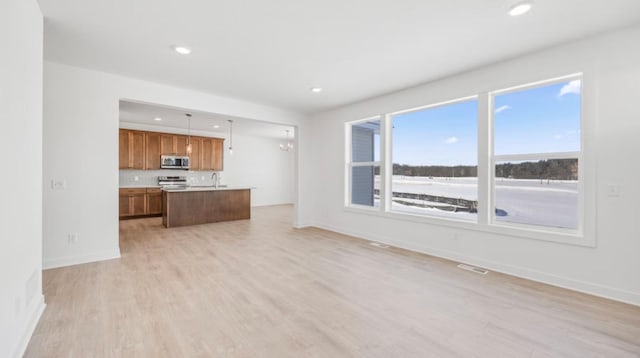 unfurnished living room with a chandelier, recessed lighting, a sink, baseboards, and light wood-type flooring