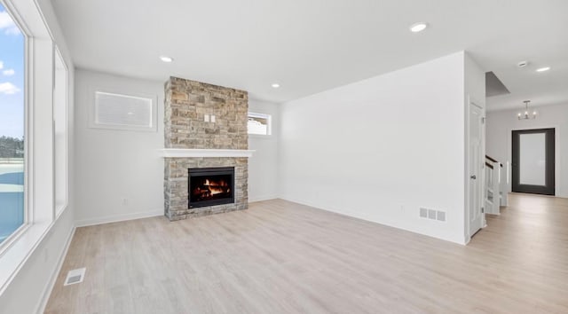 unfurnished living room with visible vents, a stone fireplace, light wood-style flooring, and recessed lighting