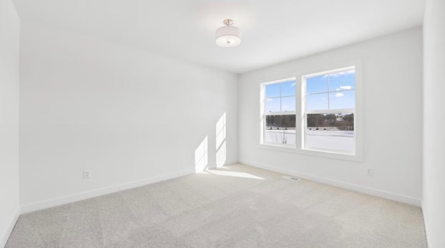 spare room with baseboards and light colored carpet