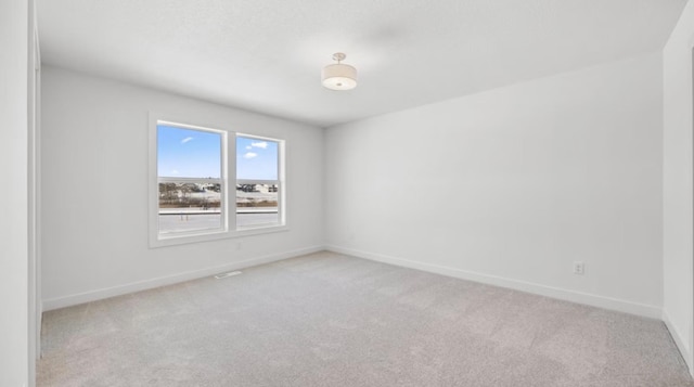 spare room with light colored carpet and baseboards