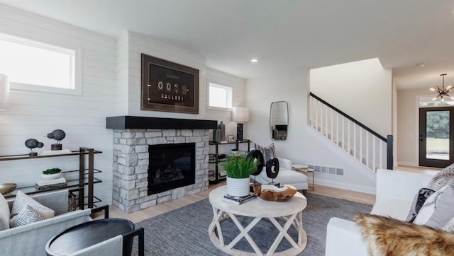 living room with a chandelier, wood-type flooring, and a stone fireplace