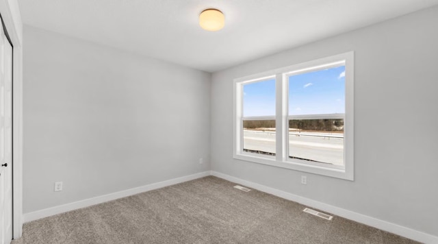 spare room featuring carpet flooring, visible vents, and baseboards