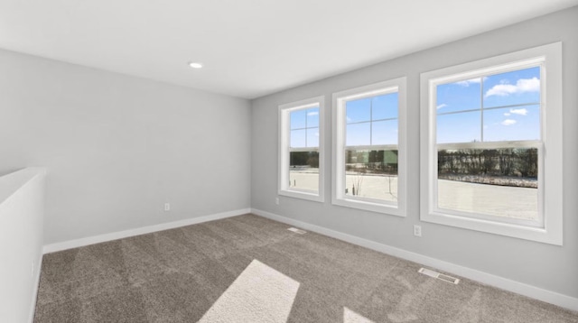 empty room featuring carpet floors, recessed lighting, visible vents, and baseboards