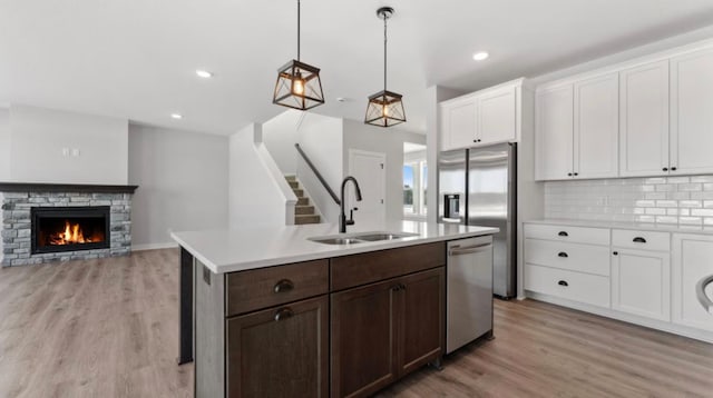 kitchen featuring light wood finished floors, stainless steel appliances, light countertops, white cabinets, and a sink