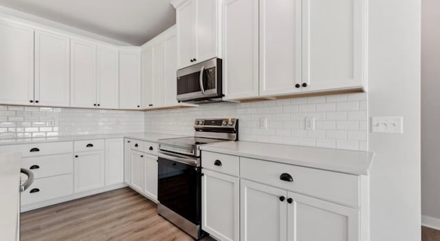 kitchen with stainless steel appliances, light wood-type flooring, light countertops, and white cabinets