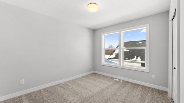 spare room featuring carpet, visible vents, and baseboards