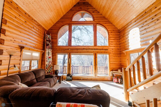 living room with a wealth of natural light, log walls, and high vaulted ceiling