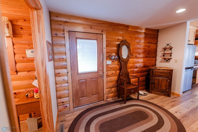 foyer entrance featuring rustic walls and light wood-type flooring