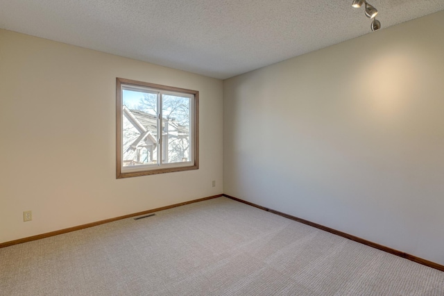 carpeted empty room featuring a textured ceiling