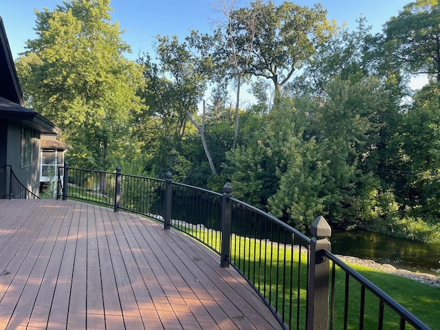 wooden terrace with a yard and a water view