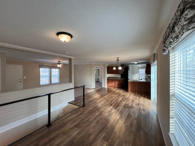 interior space featuring a textured ceiling, ornamental molding, dark wood-type flooring, and ceiling fan