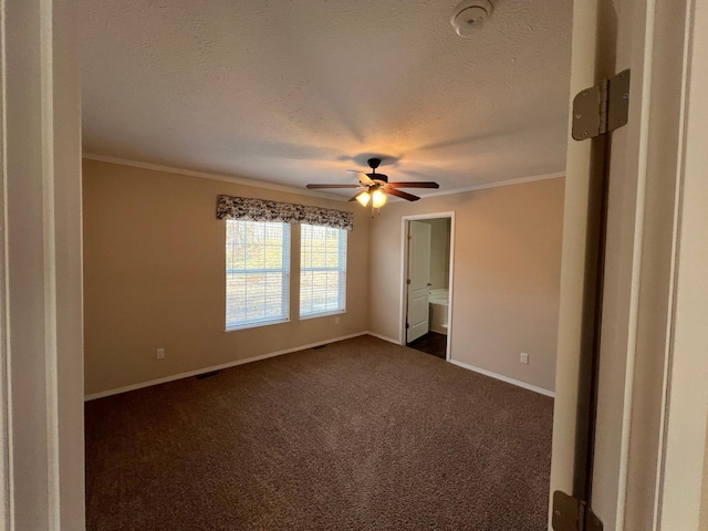 unfurnished bedroom with dark colored carpet, ornamental molding, ensuite bathroom, ceiling fan, and a textured ceiling