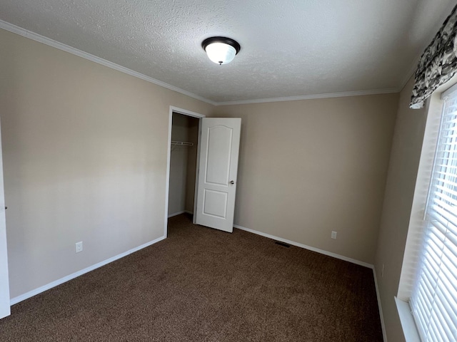 unfurnished bedroom featuring a closet, a textured ceiling, dark carpet, and crown molding