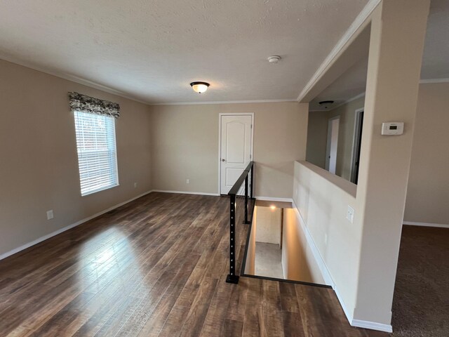 empty room featuring ornamental molding, a textured ceiling, and dark hardwood / wood-style floors