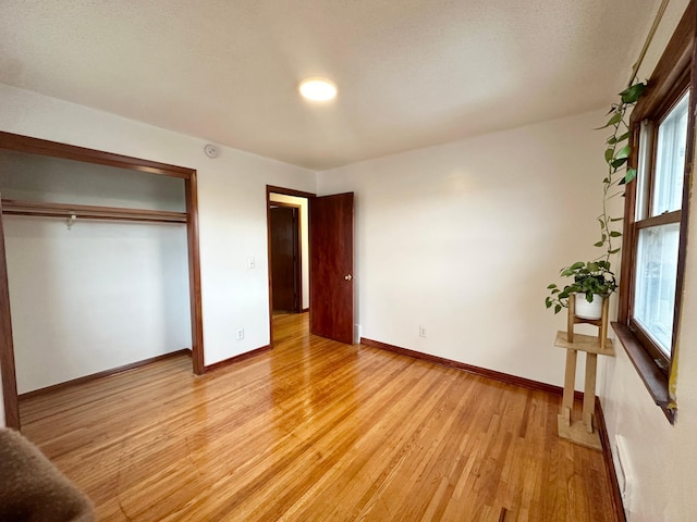 unfurnished bedroom with light wood-type flooring and a closet