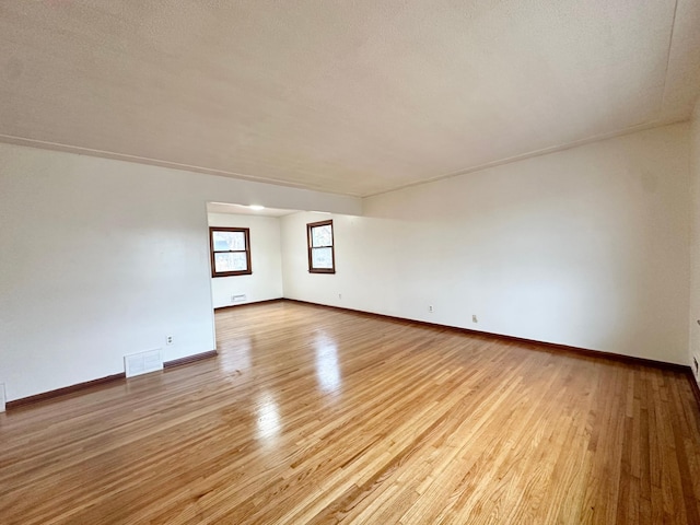 empty room featuring a textured ceiling and light hardwood / wood-style flooring