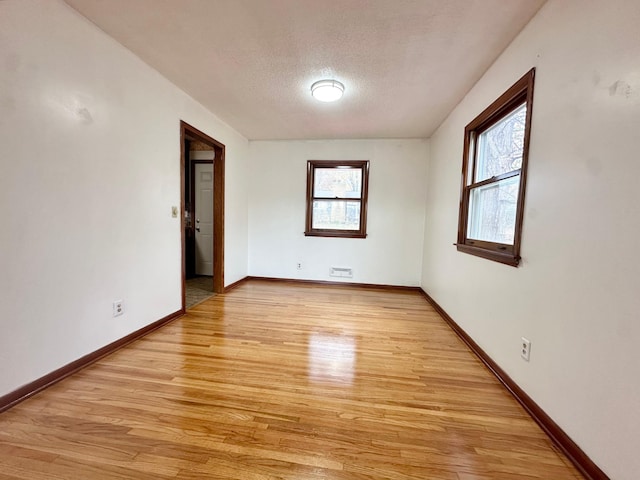 spare room featuring light wood-type flooring and a textured ceiling