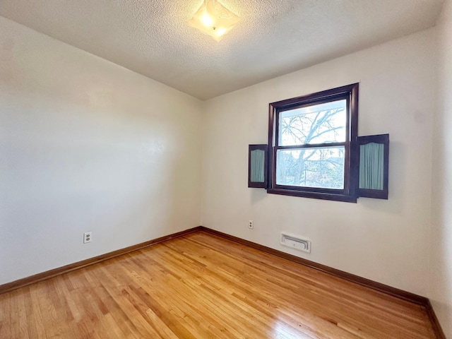 unfurnished room with wood-type flooring and a textured ceiling