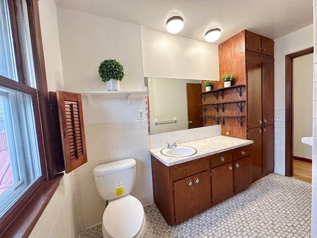 bathroom with tile patterned flooring, vanity, toilet, and tile walls