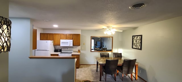 kitchen with light colored carpet, white appliances, ceiling fan, kitchen peninsula, and a textured ceiling