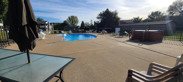 view of swimming pool featuring a hot tub and a patio area