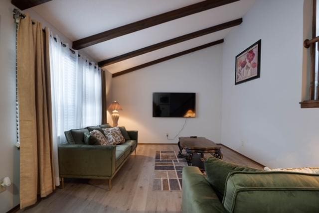 living room featuring light hardwood / wood-style flooring and vaulted ceiling with beams