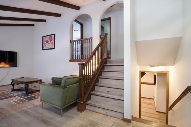 stairway featuring wood-type flooring and beam ceiling