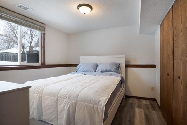 bedroom with dark hardwood / wood-style floors and a closet