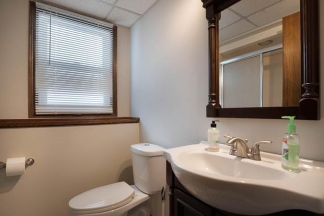 bathroom with a drop ceiling, vanity, toilet, and a shower with shower door